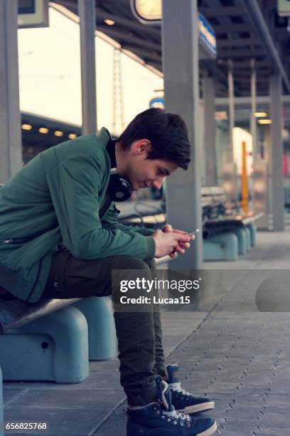 adolescente ascolta musica e aspetta sul treno - lässige kleidung foto e immagini stock