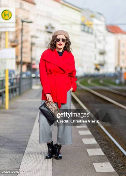 Nisa Aslan wearing a beige beret, red wool coat, grey wide leg cropped pants, leopard print clutch on March 22, 2017 in Berlin, Germany.