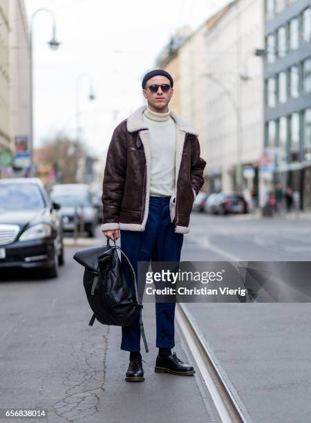 Lucas Christiansen wearing a brown leather jacket, wool hat beanie, navy pants, backpack, sunglasses, sweater on March 22, 2017 in Berlin, Germany.
