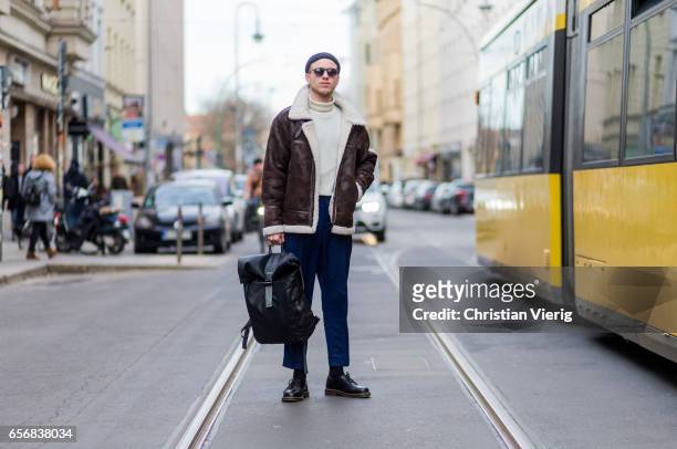 Lucas Christiansen wearing a brown leather jacket, wool hat beanie, navy pants, backpack, sunglasses, sweater on March 22, 2017 in Berlin, Germany.