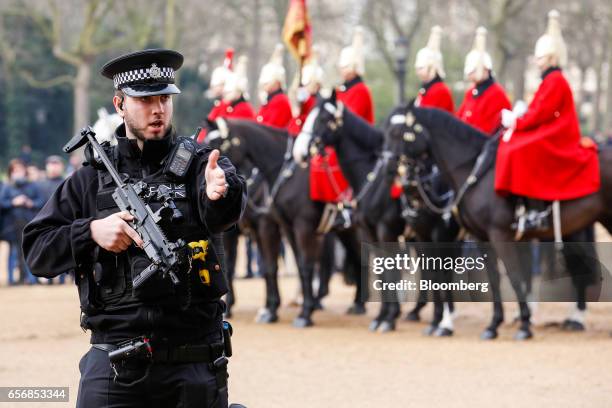 An armed British police officer patrols in Horse Guards Parade as tourists watch after the terror attack at Westminster in central London, U.K., on...