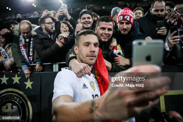 Lukas Podolski of Germany takes a selfie with supporters after playing his final international match for Germany during the international friendly...