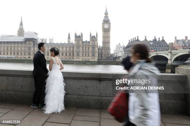 Couple prepare to pose for their wedding pictures by Westminster Bridge in central London on March 23, 2017 after the bridge reopened to traffic...