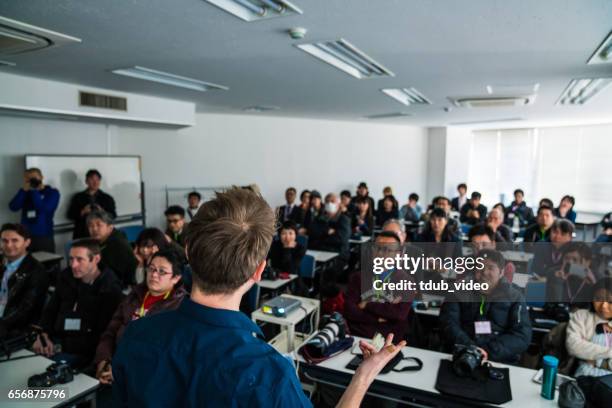 mid adult man giving a presentation or speech to a large group of people - japan training session stock pictures, royalty-free photos & images