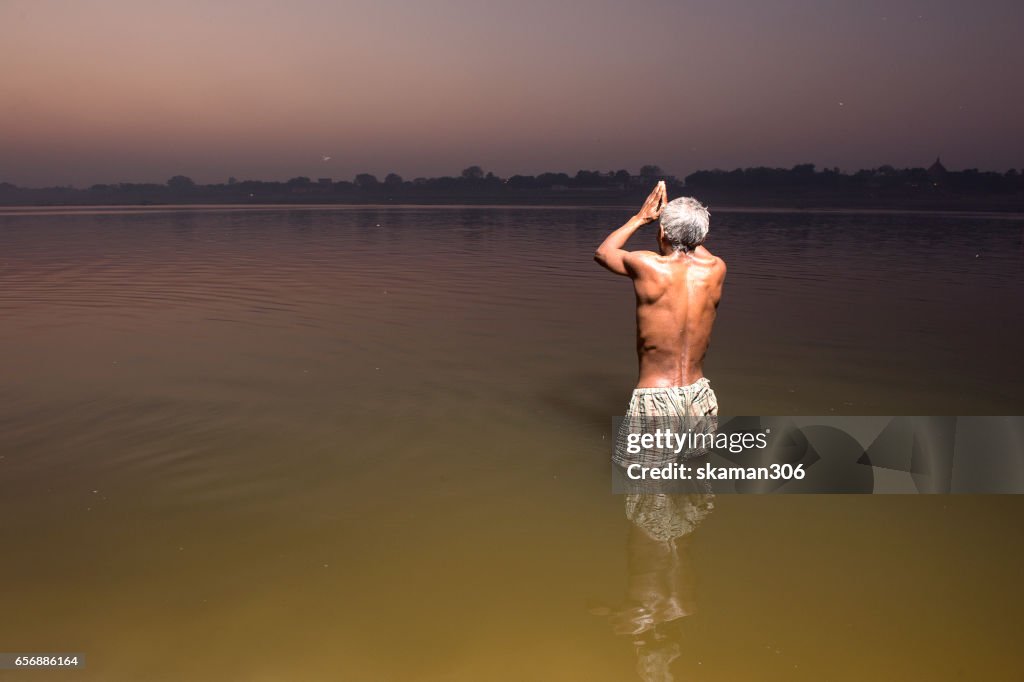 Sadhu against the sun praying and holi dip in  Ganges river near Raj ghat varanasi india
