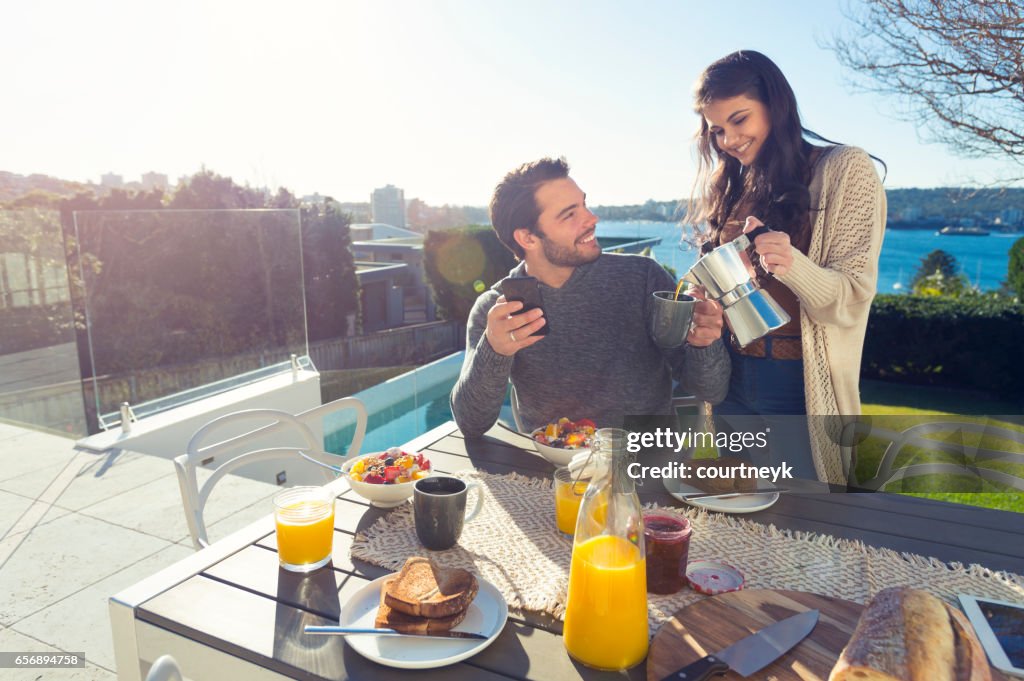 Pareja comiendo desayuno al aire libre.