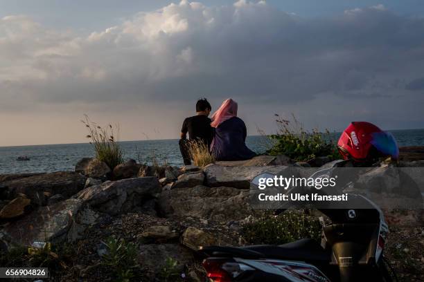 Couple sit as they enjoy their time at the beach which goes against the prevailing sharia law in Aceh on March 22, 2017 in Banda Aceh, Indonesia....