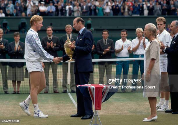 Boris Becker of West Germany receives the trophy for the Wimbledon men's singles championship from The Duke of Kent, with The Duchess of Kent and...