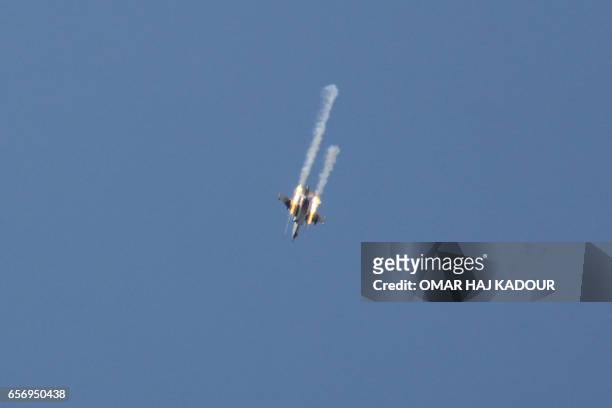 Picture taken on March 23 shows a Syrian army jet firing rockets over the village of Rahbet Khattab in the Hama province. Jihadists and allied rebels...
