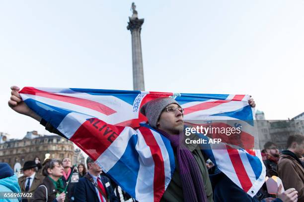 Man holds a Union flag a during a vigil in Trafalgar Square in central London on March 23, 2017 in solidarity with the victims of the March 22 terror...