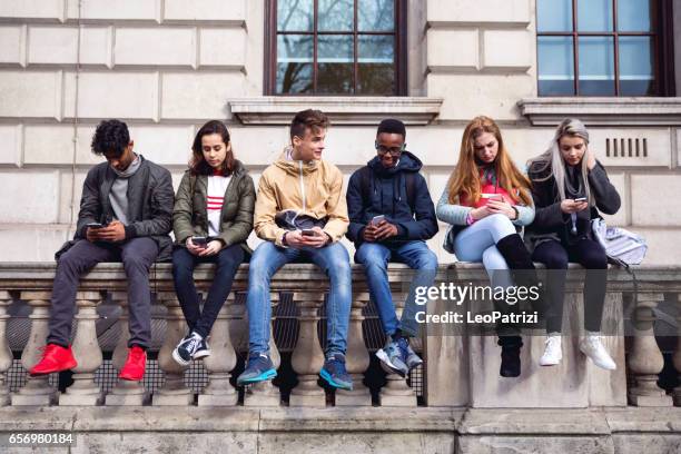 青少年學生在學校休息上使用智慧手機 - adolescent 個照片及圖片檔