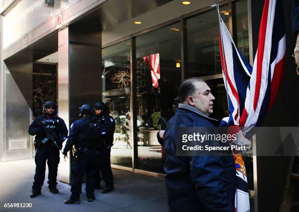 Worker takes down the British flag in front of the United Kingdom Consulate as counter terrorism police stand guard lower Manhattan a day after a...