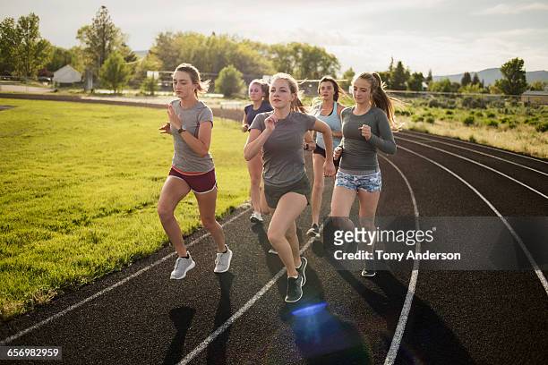 young women runners rounding turn on track - girls on train track stock pictures, royalty-free photos & images