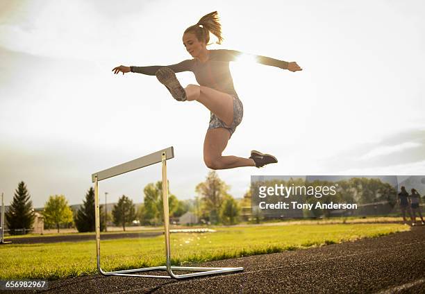 young woman hurdler on school track - leichtathletik stock-fotos und bilder