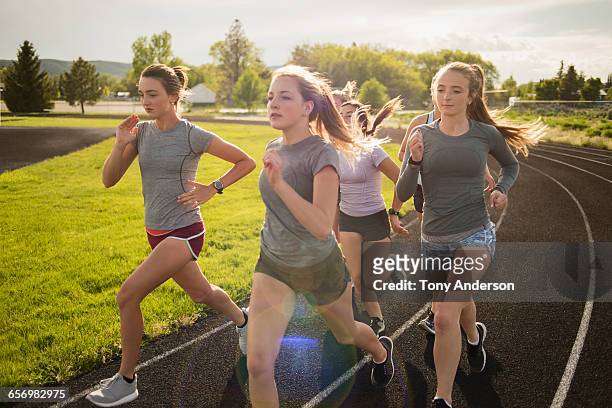 yong women runners rounding turn on track - girls on train track stock pictures, royalty-free photos & images