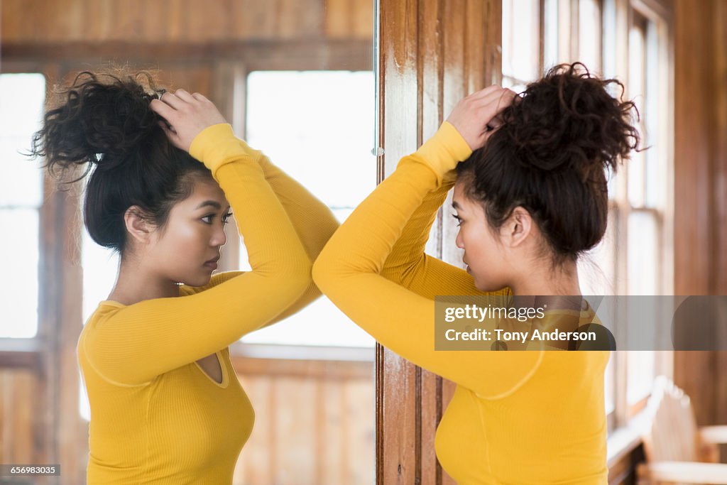 Young woman looking into mirror in rustic lodge