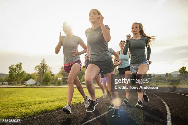 young women runners rounding turn on track - 女の子走る ストックフォトと画像