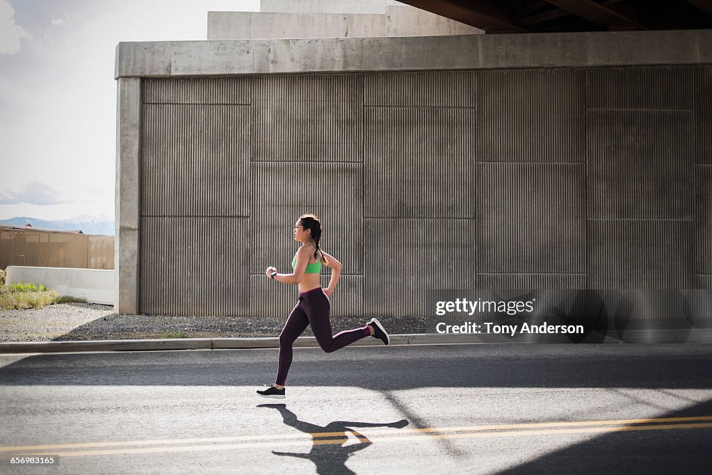 Young woman running under freeway overpass