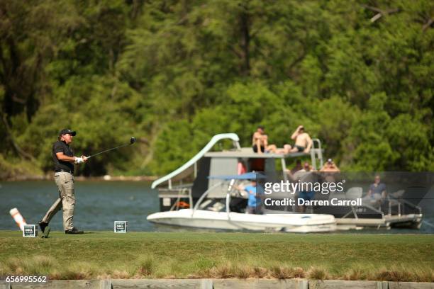 Phil Mickelson tees off on the 14th hole of his match while fans watch from a boat during round two of the World Golf Championships-Dell Technologies...