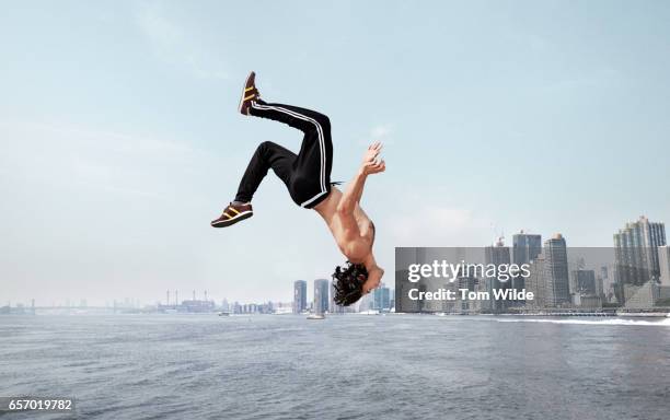 caucasian male free running along a wall with the manhattan skyline in the background - fare le capriole all'indietro foto e immagini stock