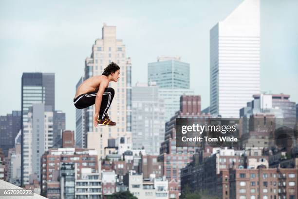 caucasian male free running and jumping with the manhattan skyline in the background - le parkour fotografías e imágenes de stock