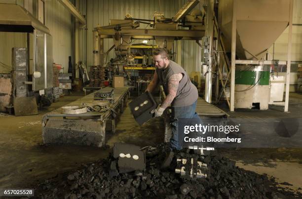 An employee unearths aluminum components from green sand molds while working in the foundry at the Super Vac Manufacturing Co. Production facility in...