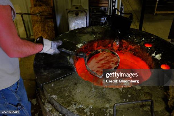 An employee scoops melted aluminum to pour into a mold while working in the foundry at the Super Vac Manufacturing Co. Production facility in Fort...