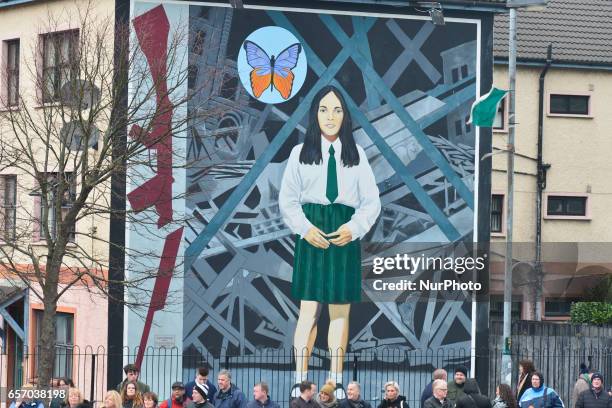 People await on the street in front of one of many murals for the coffin of former Northern Ireland Deputy First Minister Martin McGuinness, in the...