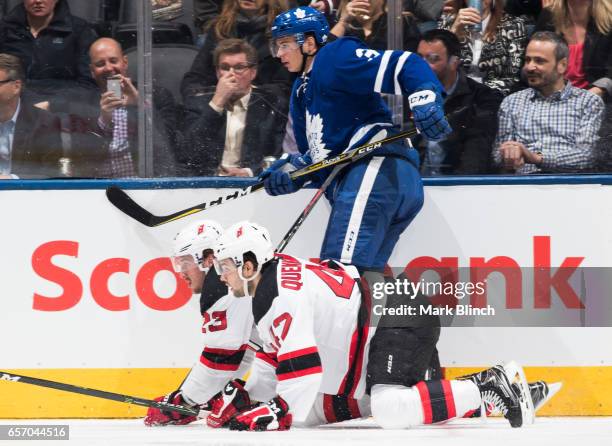Alexey Marchenko of the Toronto Maple Leafs follows the play as Stefan Noesen and John Quenneville of the New Jersey Devils get up off the ice during...