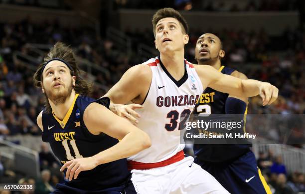 Zach Collins of the Gonzaga Bulldogs vies for position with Nathan Adrian and Jevon Carter of the West Virginia Mountaineers in the first half during...