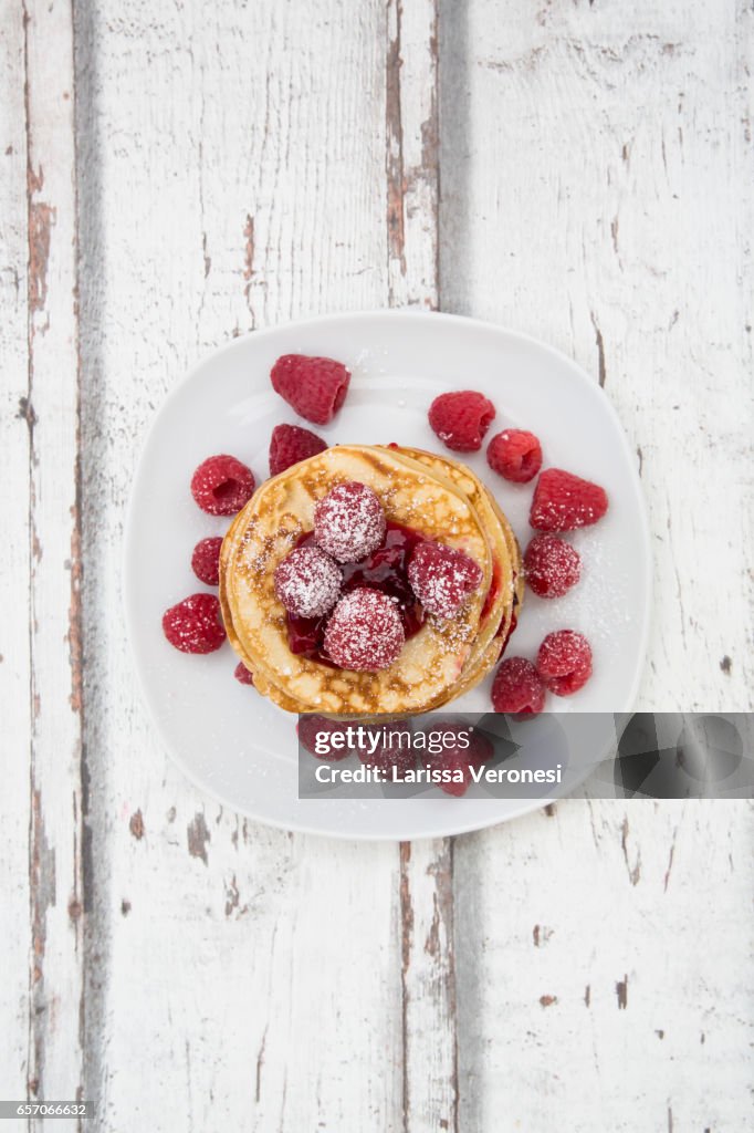 Stack of pancakes with raspberry sauce and raspberries