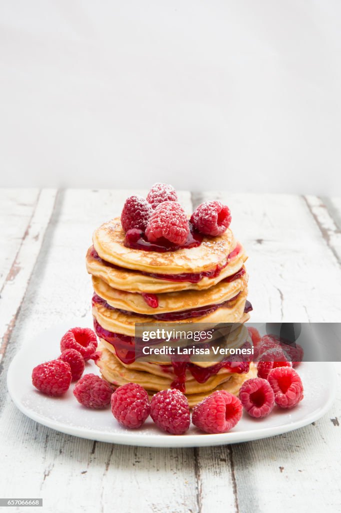 Stack of pancakes with raspberry sauce and raspberries