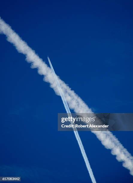 Contrails left by jet aircraft streak the sky over Santa Fe, New Mexico. While the contrails might appear to show a 'near miss' between two aircraft,...