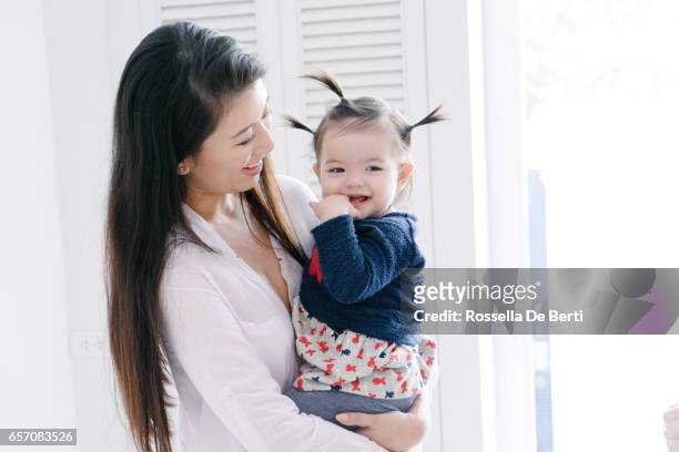若い母娘を運ぶと再生 - 指をくわえる ストックフォトと画像