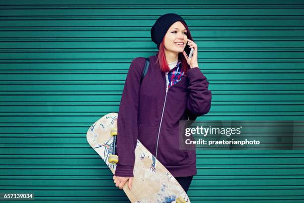 girl is standnding to the wall and talking using her mobile phone - womens free skate imagens e fotografias de stock