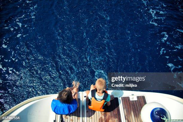 girl and boy enjoying vacation on sailboat - life jacket stock pictures, royalty-free photos & images