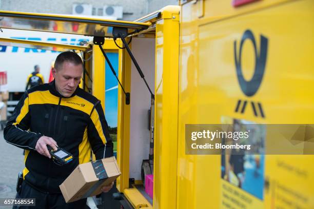 Postal worker scans a parcel before loading it into a StreetScooter emission-free electric light commercial vehicle for distribution at a Deutsche...