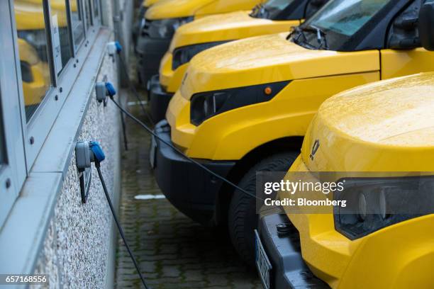 Electric charging cables sit connected to StreetScooter emission-free electric light commercial vehicles , developed by Deutsche Post AG, at a...