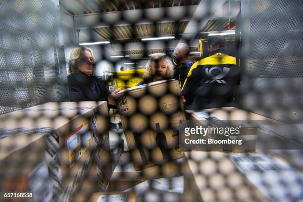 Postal workers load a parcel container in the sorting office of a Deutsche Post AG delivery station in Hamburg, Germany, on Tuesday, March 7, 2017....