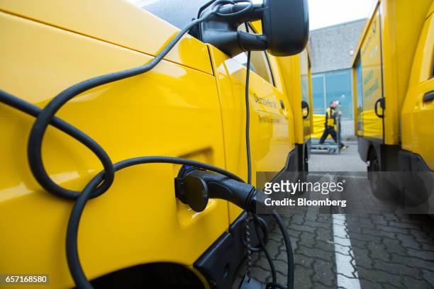 An electric charging cable sits connected to StreetScooter emission-free electric light commercial vehicle , developed by Deutsche Post AG, outside a...