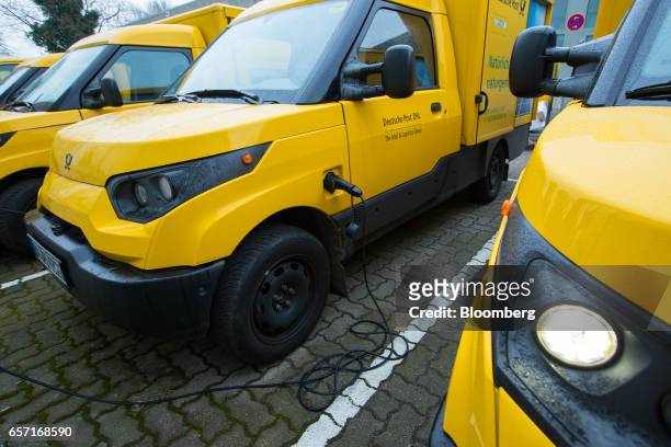 An electric charging cable sits connected to a StreetScooter emission-free electric light commercial vehicle , developed by Deutsche Post AG, outside...
