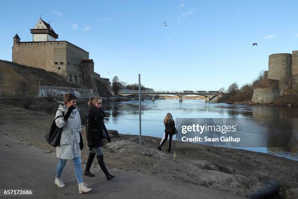 Russian-speaking people walk along a promenade along the Narva River below Hermann Castle and opposite Ivangorod Fortress, which is on the Russian...