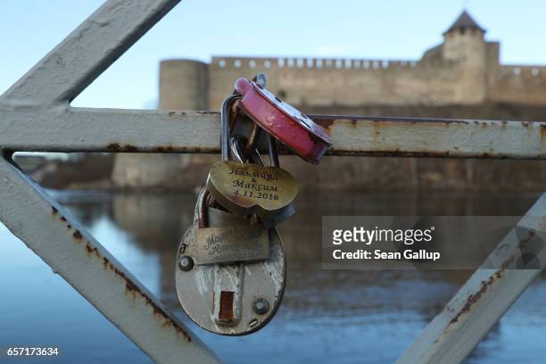 Love locks hang attached to a bridge on the Estonian side of the Narva River opposite Ivangorod Fortress, which is on the Russian side, on March 23,...