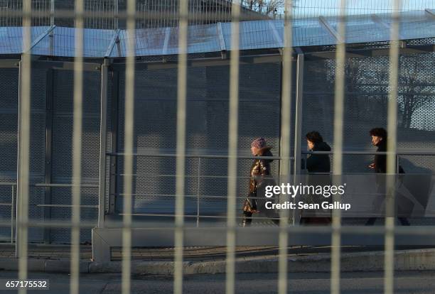 Pedestrians cross from Russia into Estonia behind a fence along the bridge over the Narva River on March 23, 2017 at Narva, Estonia. Estonia is a...