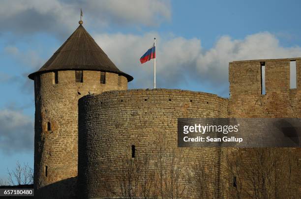 Russian flag flies over Ivangorod Fortress, which lies on the Russian side of the Narva River, as seen from the western, Estonian side on March 23,...