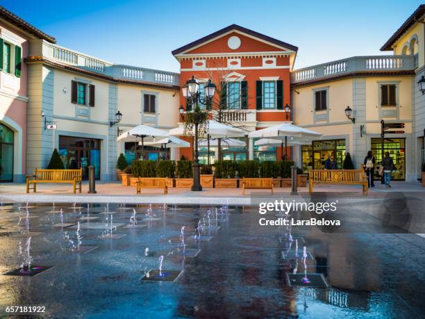 serravalle scrivia - 17. märz 2017: blick auf den neuen teil des outlet in serravalle scrivia, menschen zu fuß und auf der suche nach schaufenster - fabrikverkauf stock-fotos und bilder