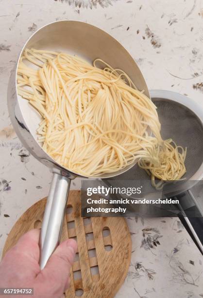 draining dried egg noodles through a sieve. - sieve stock pictures, royalty-free photos & images