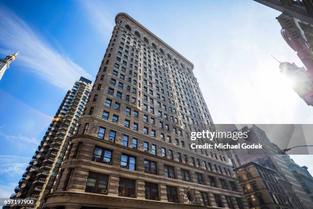 stunning wide angle shot of the flatiron building against blue sky with sweeping clouds with different street scenes below - flatiron building stockfoto's en -beelden