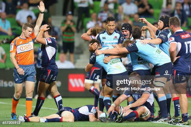 Bernard Foley of the Waratahs scores the winning try as teammates come in to celebrate during the round five Super Rugby match between the Rebels and...