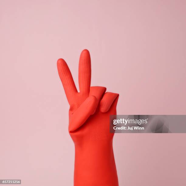 hand in red rubber glove making peace sign - rosa handschuh stock-fotos und bilder